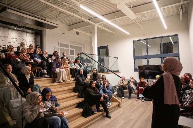 A woman speaking to a group of female Muslims at an event