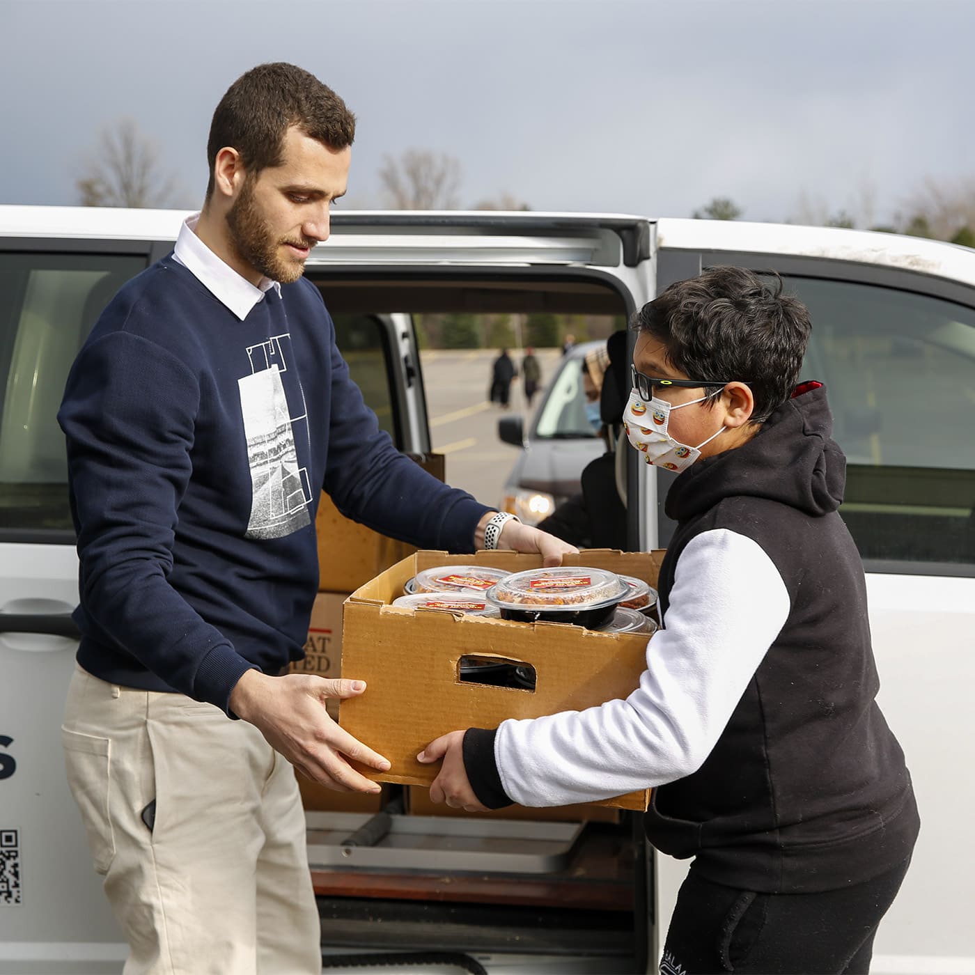 ISNA Canada volunteer distributing food to a young boy