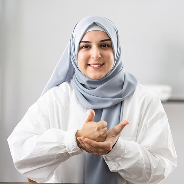 A hijab-wearing woman using ASL to communicate