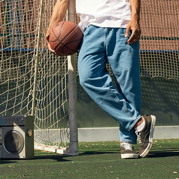 A young boy holding a basketball on a soccer field next to a stereo